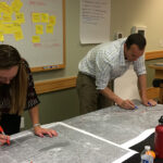 Two people collaborating on a map in a conference room, utilizing services.