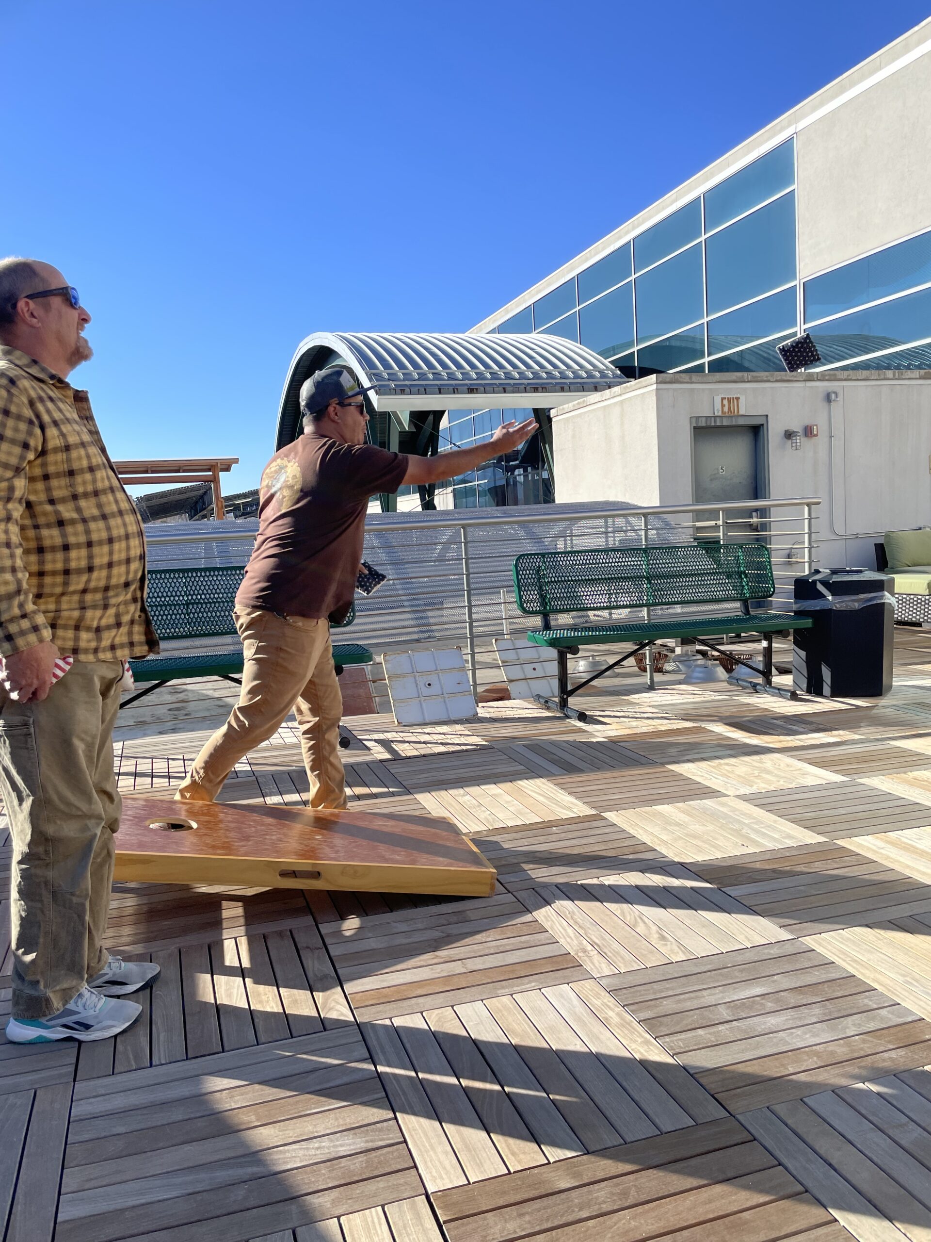 Two men playing frisbee on a deck.