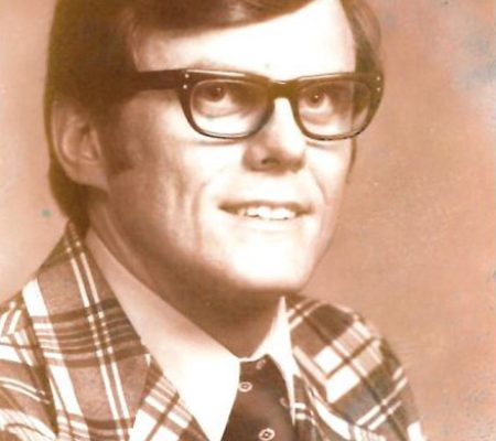 An old photo of a man wearing glasses and a plaid suit at Lakewood, Colorado.