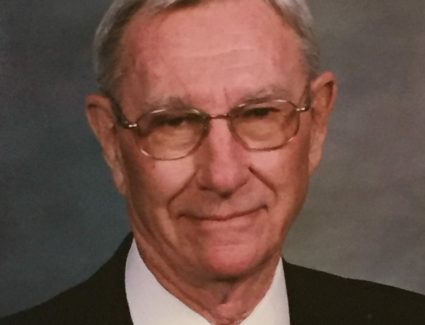 An older man from Muller Engineering Company in Lakewood, Colorado, wearing a suit and tie, is posing for a photo.